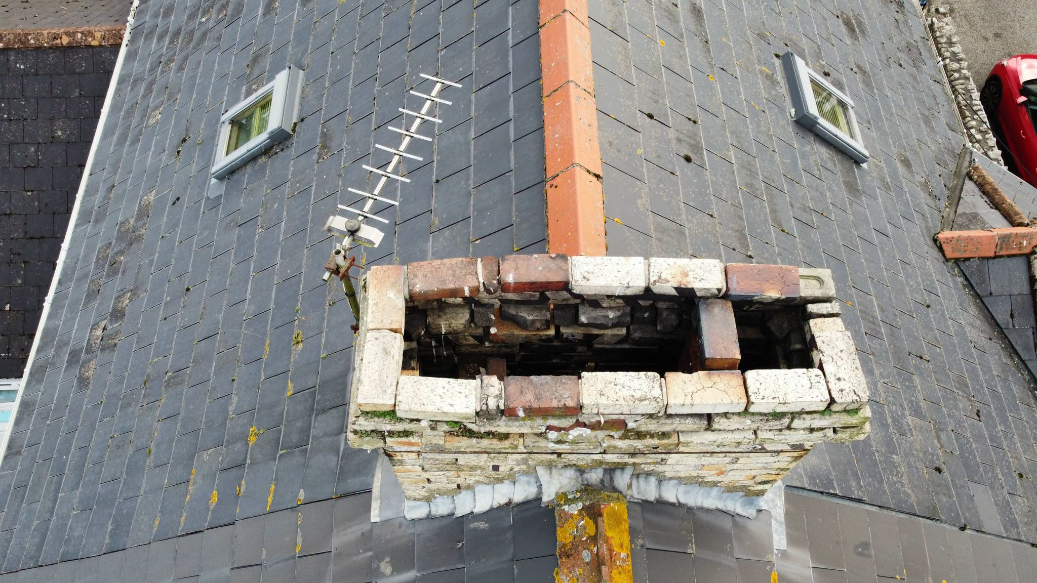 The chimney stack standing on a slate roof with two roof windows