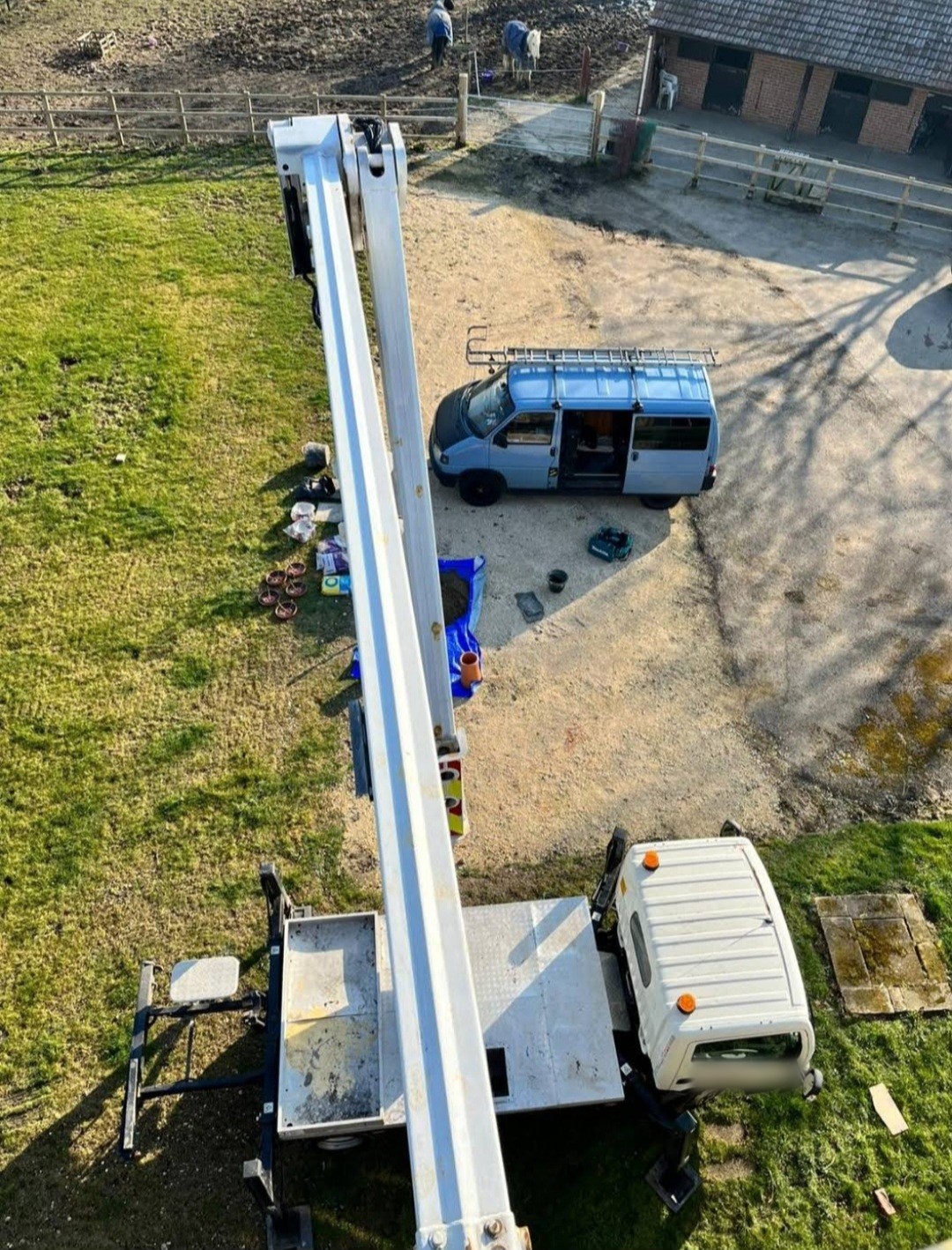 Looking straight down from an access platform basket at the vehicles and kit parked on the ground