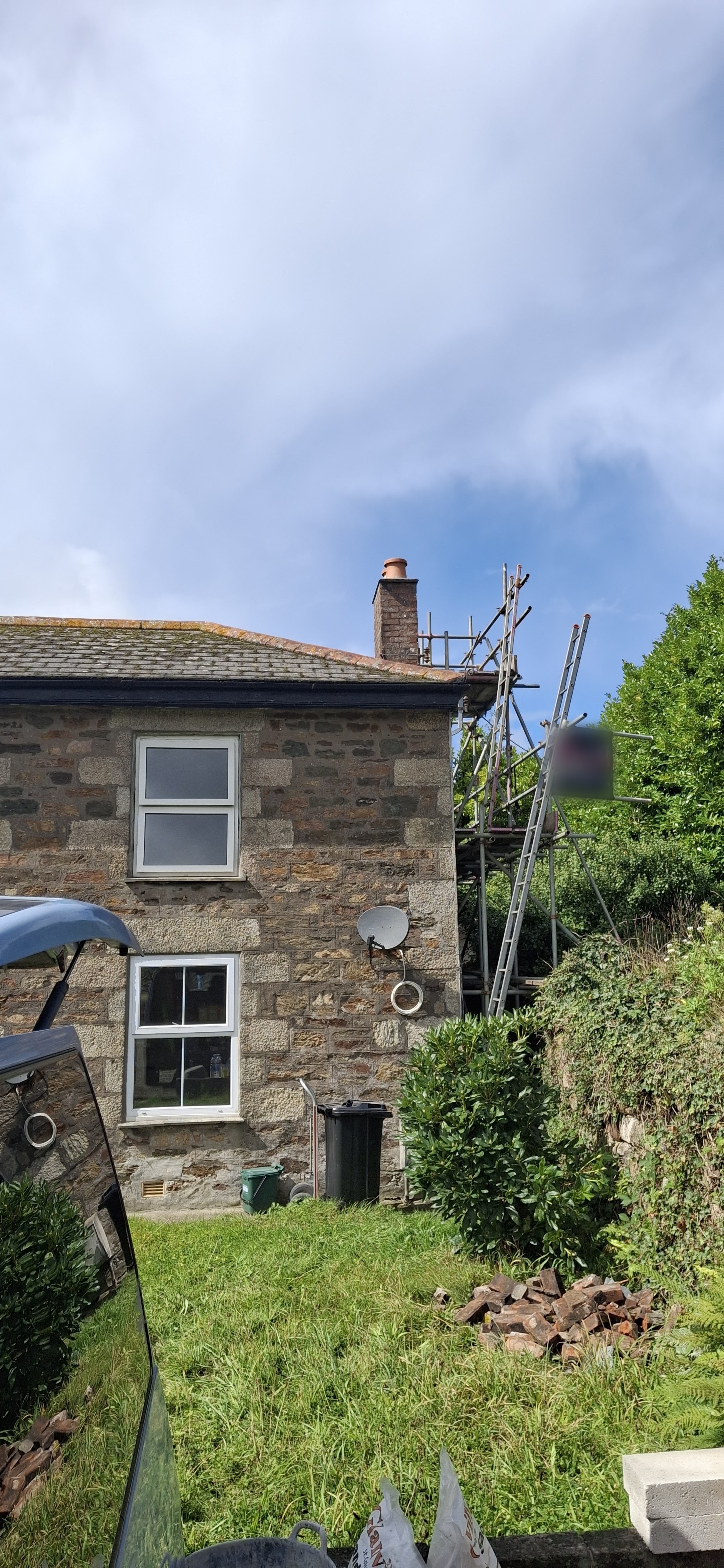 A Cornish granite cottage with a ladder and scaffold tower up to its brick chimney