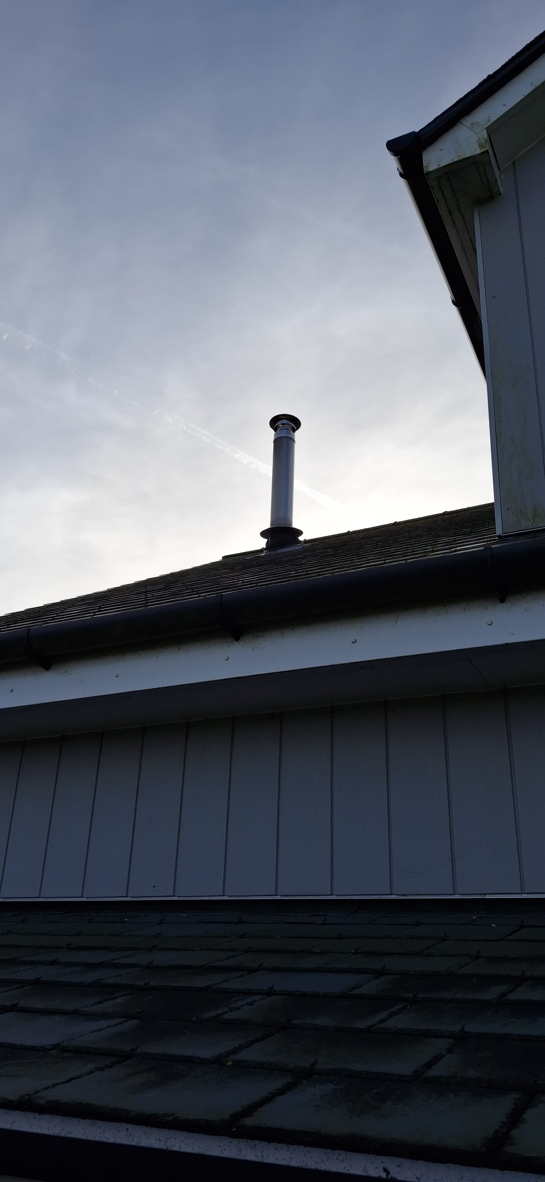 A stainless steel flue terminal rising above a roof, seen from below