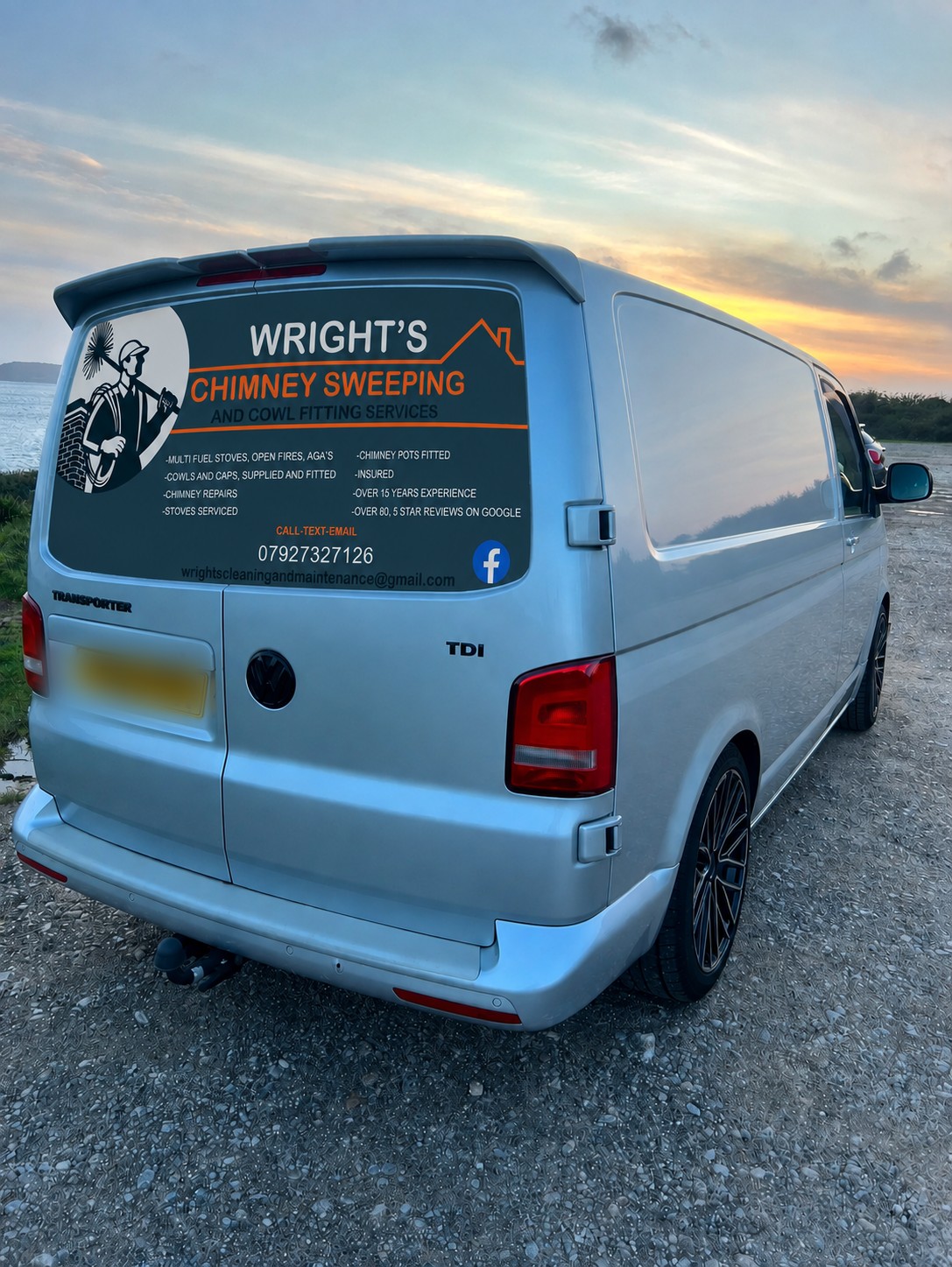Wright's Chimney Sweeping van, a silver VW Transporter with the logo, service list and phone number on the back, parked by the sea at sunset